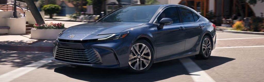 A blue Toyota Avalon sedan driving through a city street, showcasing its sleek design.